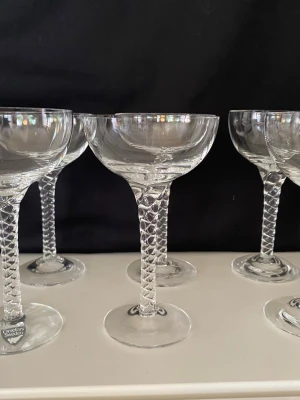 Sju Orrefors glas - likörglas/snaps i serien Anne - 7 st jättefina likörglas från Orrefors med mönstrad fot. Från den klassiska glasservisen "Anne", formgiven av Anne Nilsson för Orrefors. En del av glasen är helt nya.  Jag har lagt upp lite mått inne i bilderna.  En del kallar dessa även för snapsglas men jag kallar de likörglas.  Hämtas i Örby/Älvsjö/Stockholm  Skickas ej    