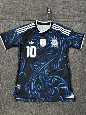 Argentina Messi matchtröja Adidas ➡️Priset går att förhandla ✅ - Snygg svart och blå Argentina matchtröja från Adidas med Messi och nummer 10 på ryggen. Tröjan har vita detaljer, tre ränder på axlarna och coolt blått mönster över hela tyget. Tillverkad i lätt och ventilerande material, perfekt för fotboll eller träning.