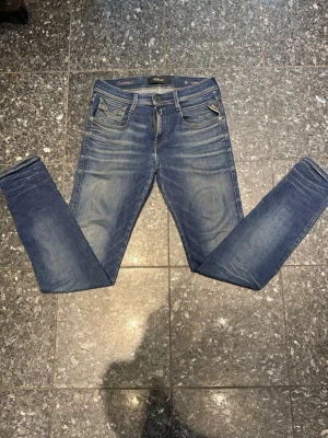 Blå slim jeans från replay  - Snygga blå slimjeans från replay med klassisk femficksdesign och dragkedja. Jeansen har en tvättad look med lätt slitning och smal passform som sitter tajt hela vägen ner. Perfekta till sneakers eller boots och passar till många olika stilar.