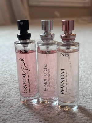 NG parfymtrio Crystal Pink, Bella Vida, Phenom - Säljer tre eleganta parfymflaskor från NG: Crystal Pink, Bella Vida och Phenom. Flaskorna är cylinderformade i glas med olika färg på vätskan och metalliska sprayhuvuden i svart, silver och rosé ‼️15 ml ‼️ Perfekt för dig som vill testa olika dofter.