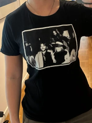 Svart t-shirt med tryck från Limitato - Säljer en svart t-shirt från Limitato med ett stort svartvitt fototryck på bröstet. T-shirten har rund hals och korta ärmar. Materialet känns mjukt och skönt, troligtvis bomull. Perfekt för dig som gillar grafiska motiv och streetwear-vibe.