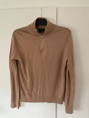 Som ny gyllenbrun Riley merinoull half zip herr M - En väldigt snygg helt ny brun Riley merinoull tröja herr M. Perfekt nu till sommaren! Inga hål eller fläckar i superfint nyskick så riktigt kap! Tveka inte vid minsta fråga eller fundering.
