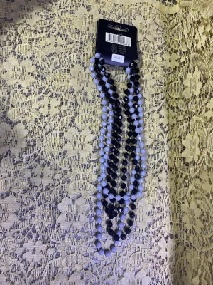 Svart och vitt pärlhalsband - Snyggt halsband med flera rader av facetterade pärlor i svart och vitt. Halsbandet har en trendig och ungdomlig look, perfekt för att lyfta vilken outfit som helst. Pärlorna är troligtvis av plast och ger ett coolt, glansigt intryck.