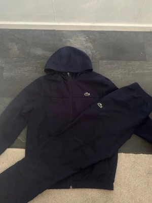 Svart tracksuit från Lacoste - Säljer nu min Lacoste tracksuit denne i jätte bra skick och perfekt inför sommar kvällar skriv om du har några funderingar byten funkar också😊