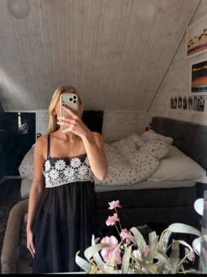 Svart nattlinne med spetsdetaljer - Snyggt svart nattlinne med tunna axelband och vit spets upptill med blommönster. Lätt och luftig modell som känns både söt och stilren. Perfekt för mysiga kvällar hemma men man kan även använda de som klänning.