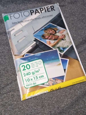 Fotopapper - Fotopapper i storlek 10x15 cm, 240 g/m², för utskrift av bilder med hög upplösning upp till 9600 dpi. Förpackningen innehåller 20 ark. Papperet är vitt och har en blank yta, perfekt för att skriva ut foton hemma med skrivare.