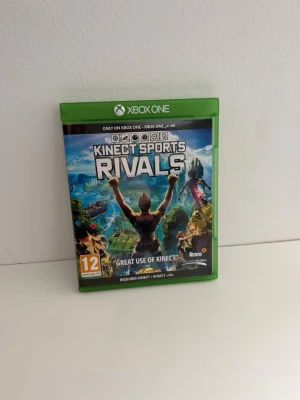 Kinect Sports Rivals Xbox One - Kinect Sports Rivals till Xbox One, ett sportspel som kräver Kinect. Spelet kommer i en grön plastbox med matchande skiva. Omslaget har färgstarka illustrationer och spelet är utvecklat av Rare Studios. Perfekt för dig som gillar rörelsebaserade spel. Använd men i mycket gott skick