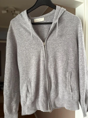 Grå Kashmir tröja - Mjuk och stilren grå Kashmir hoodie från sayless. Tillverkad i en tunn, skön stickad kvalitet som känns lyxig och passar perfekt till en sommarkväll. Enkel och clean design som funkar till det mesta.
