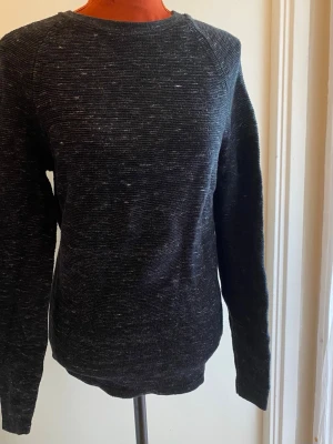Mörkgrå melerad stickad tröja S - Tröja från Selected Homme i mörkgrå nyans. Tröjan har långa ärmar och en rund halsringning. Passar bra för en avslappnad stil. Längd: 68 cm Bystvidd: 45 cm  Inga bilder på mig! Katter finns i hemmet!