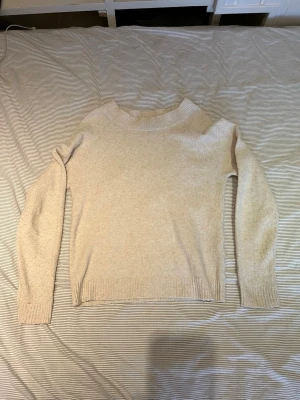 Beige stickad tröja VERO MODA - Ljus-beige stickad tröja med rund halsringning och långa ärmar. Tröjan har ribbade muddar vid ärmslut och nederkant. Från Vero Moda