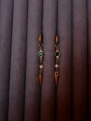 Guldiga örhängen med pärldetalj - Säljer ett par trendiga guldiga örhängen med gröna stenar, små vita pärlor och spetsiga hängande detaljer. Örhängena har en cool och modern design med ringfäste och kedjor. Perfekta för dig som gillar unika accessoarer med lite edge.