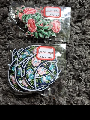 Broderade tygmärken med blommor - Två olika set broderade tygmärken med blommotiv. Ena setet har rosa blommor och gröna blad, det andra har runda märken med blå, rosa och vita blommor samt gröna detaljer. Perfekta att sy eller stryka på jackor, jeans eller väskor för en personlig touch. 40 stycken