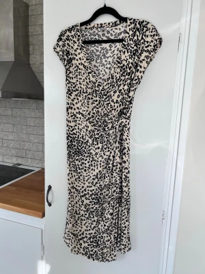 Leopardklänning med definierad midja - Säljer en klänning i ett beiget/svart leopardmönster, från Indiska. V-ringad, knälång och tightare i midjan.  Köp second hand, men aldrig använd! 👐🏻