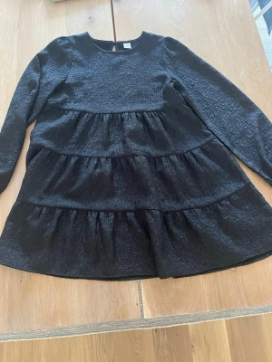Svart långärmad klänning Lindex - Säljer en svart långärmad klänning från Lindex. Klänningen har rund halsringning och knäppning bak i nacken. 
