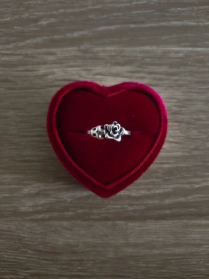 Silverfärgad ring med ros och dödskalle - ring i storlek 18,1mm, silverfärgad. 