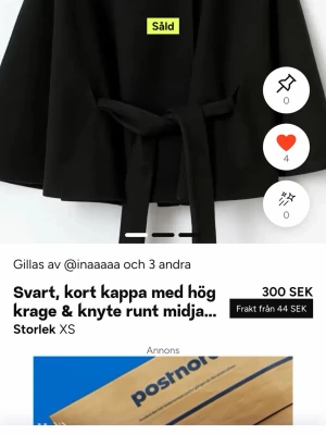 Svart kort kappa med knytband - Stilren svart kappa med hög krage och knytband i midjan. Modellen är kort och har en enkel, modern design utan synliga knappar. Perfekt för dig som gillar minimalistisk stil och vill ha en kappa som funkar till många looks.