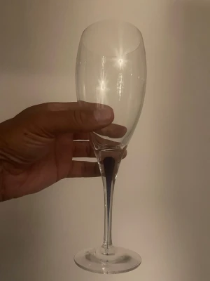Elegant champagneglas i glas - Säljer ett stilrent champagneglas med hög fot och smal kupa. Glaset är helt transparent och har en klassisk form som passar perfekt till festliga tillfällen. Materialet är glas och designen är enkel men elegant.