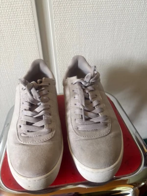 Beige sneakers i mocka-look, size 37 - Snygga beige sneakers med mocka-look och klassisk låg profil. Skorna har matchande beige snören och en vit sula som ger en clean vibe. Perfekta för dig som gillar stilrena och minimalistiska sneakers. Diskreta detaljer på sidan och bekväm passform.