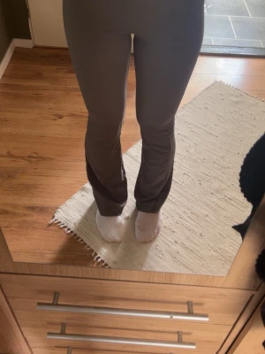 Gråa bootcut leggings - Säljer ett par gråa leggings med bootcut-modell. De har hög midja och sitter tight över låren men är utsvängda nedtill. Materialet är stretchigt och mjukt, perfekt för en avslappnad och trendig look. Inga synliga loggor eller detaljer.