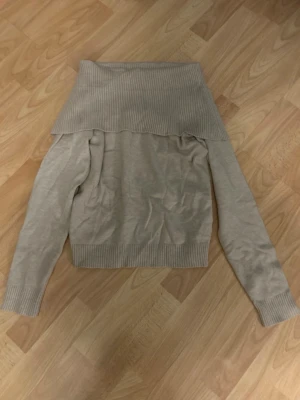 Beige off shoulder-tröja från Lindex - Snygg beige off shoulder-tröja från Lindex med bred ribbad krage och långa ärmar. Tröjan har ribbade muddar vid ärmslut och nederkant, perfekt för en trendig och avslappnad look.💗