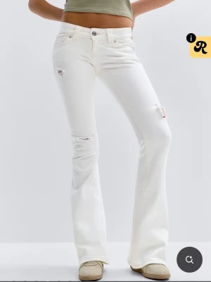 Vita low rise flare jeans Gina Tricot 14+ - Säljer ett par vita low rise flare jeans från Gina Tricot med utsvängda ben och slitna detaljer vid knäna. Jeansen har klassisk femficksdesign och låg midja. Perfekta för dig som gillar trendiga och bekväma jeans med lite edge.