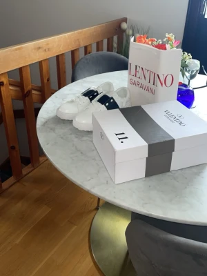 Vit box från Valentino Garavani - Vit box från Valentino Garavani med röd logga på locket. Perfekt för att förvara accessoarer eller använda som presentförpackning. Stilren och lyxig känsla med klassisk design.