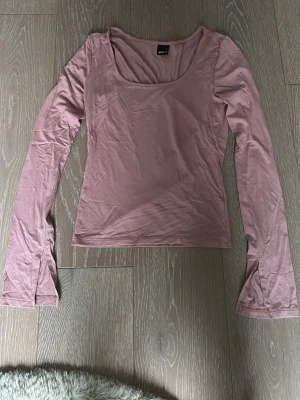 Ljusrosa långärmad tröja från Gina Tricot - Supersöt ljusrosa långärmad tröja från Gina Tricot med utsvängda ärmslut och rundad urringning. Tunn och mjuk i materialet, perfekt att styla med jeans eller kjol. Enkel men trendig design som passar till många looks.