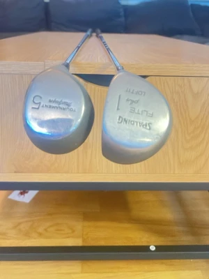Golfklubbor Spalding och Tournament pris kan diskuteras. - Två golfklubbor, en Spalding Flite Path Loft 1 och en Tournament Autograph 5. Båda har silverfärgade metallhuvuden och raka stålskaft. Perfekt för dig som vill ha klassiska klubbor till golfbanan.