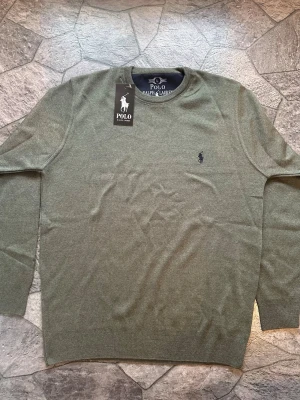  Stickad tröja Polo Ralph Lauren - Snygg olivgrön stickad tröja från Polo Ralph Lauren i storlek L/M. Perfekt för vår, höst och sommarvädret. Väldigt elegant och grisch. Pris är ej hugget i sten. Hör gärna av dig vid frågor:)