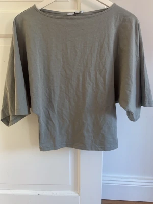 Grå loose topp från 157 - Enkel och stilren grå topp från 157 med loose passform och vida, korta ärmar. Tillverkad i mjuk bomull som känns skön mot huden. Perfekt för en avslappnad look och lätt att matcha med andra plagg.
