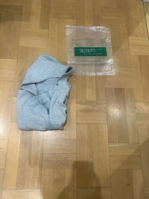 Grå hoodie från Polo Ralph Lauren - Snygg grå hoodie från Polo Ralph Lauren med dragkedja framtill och klassisk huva. Tillverkad i mjukt material och har den ikoniska lilla loggan broderad på nedre delen. Perfekt för en chill och stilren look.