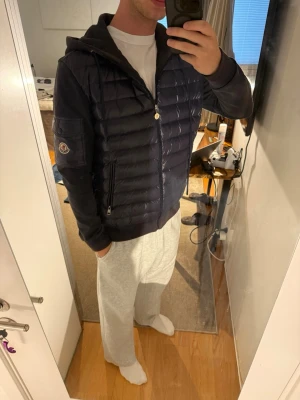 Mörkblå cardigan från Moncler - Snygg mörkblå cardigan från Moncler med quiltad front. Jackan har mjuka ärmar i sweatshirtmaterial, två dragkedjefickor fram och en Moncler-logga på ärmen. Perfekt för kalla dagar, men även vanligast. Skriv i dm för frågor. Kvitto ingår ej. 🙌