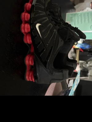 Nike Shox svarta sneakers med röd sula - Nike Shox sneakers i svart med ikonisk röd Shox-dämpning i sulan. Ovandelen är i mesh och syntetmaterial med silverfärgad Swoosh på sidan. Skorna är endast testade men säljer dom för dom ej passade 