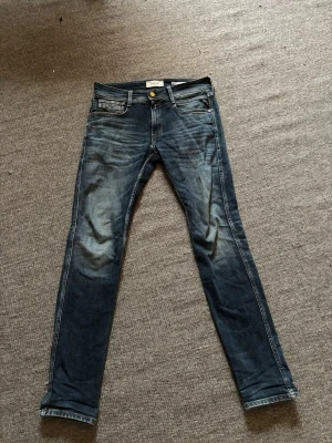 Replay Jeans - Snygga mörkblå slim fit jeans från jeans med klassisk femficksdesign och slitna detaljer på knän och lår. Jeansen har gylf med dragkedja och knapp samt kontrastsömmar. Tillverkade i bomull med en skön stretch för extra komfort.