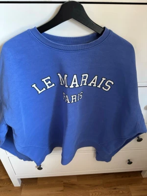 Blå sweatshirt - Snygg blå sweatshirt med trycket 'LE MARAIS PARIS' på bröstet. Den är från Lindex märke Holly & Whyte och är i storlek XL. Kan kännas lite sträv och se lite urtvättad ut. 