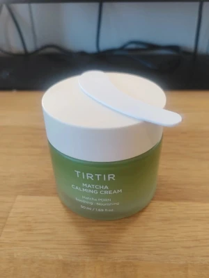 TIRTIR Matcha Calming Cream 50ml - Grön ansiktskräm från TIRTIR i en stilren glasburk med vitt lock och medföljande spatel. Innehåller matcha och är framtagen för att lugna och vårda huden. Perfekt för dig som vill ha en återfuktande och närande basprodukt.