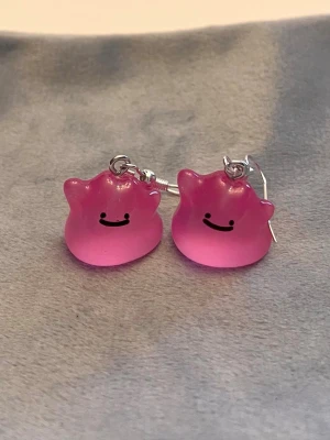Självlysande Ditto örhängen Pokémon smycke  - Så gulliga örhängen med Ditto! Berlockerna är ca 1,5 x 1,5 cm. Den är också självlysande och lyser i mörkret.