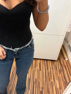 Blå bootcut jeans med låg midja - Säljer ett par blå bootcut jeans med låg midja och klassisk femficksmodell. Jeansen har en snygg tvätt och sitter tajt över låren för att sedan bli vidare nedtill. Perfekta för dig som gillar retrovibbar och vill ha ett par jeans som sticker ut.