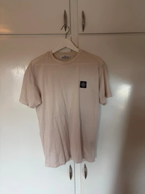 Vit t-shirt från Stone Island - Snygg vit t-shirt från Stone Island med klassisk logotyp-patch på bröstet. T-shirten har rund hals och en enkel, stilren design som passar till det mesta. Tillverkad i mjuk bomull för en skön känsla hela dagen.