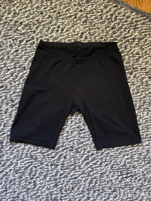 Svarta cykelshorts leggings - Svarta cykelshorts i stretchigt material med resår i midjan. Klassisk och enkel design, perfekta till sommaren eller träning. Mjuka och bekväma med knälång passform. Lapp bortklippt men minns att dem är köpta i en sportaffär.