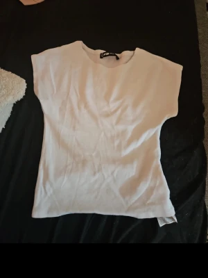 Vit ärmlös topp från Gina Tricot - En enkel och stilren vit topp från Gina Tricot. Toppen är ärmlös med rund halsringning och har en rak, loose passform. Perfekt att matcha med jeans eller kjol för en clean look.