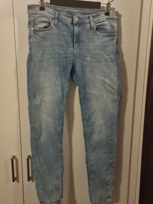 Ljusblå slim fit jeans - Säljer ett par ljusblå slim fit jeans med klassisk femficksdesign och normalhög midja. Jeansen har en tvättad look och raka ben. Materialet är denim i bomull. Perfekta för en avslappnad och trendig stil.