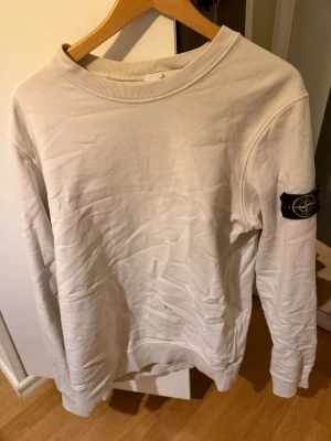 Vit sweatshirt från Stone Island - Säljer denna ”ÄKTA” stone island sweatshirt köpt från NK när jag köpte den kosta den 2400 men har gått upp i pris sedan dess. Då den har en fläck som jag försökt få bort men är inte mästare på att tvätta tyvärr därav priset