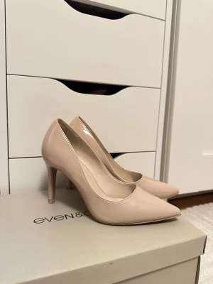 Beige lackpumps från Even&Odd - Snygga pumps i beige lack från Even&Odd med spetsig tå och smal klack. Skorna har en klassisk siluett och en glansig finish som ger en elegant touch till din outfit. Perfekta för dig som gillar stilrena och trendiga skor.