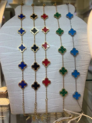 Färgglada armband med klöverhängen - Snygga armband med fyrklöverformade hängen i blått, svart, rött och grönt. Hängena är infattade i guldfärgad metall och sitter på tunna kedjor. Perfekt accessoar för att addera färg till din stil.