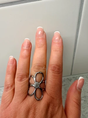 Stor silverfärgad blomring - Säljer en stor och iögonfallande ring i silverfärgad metall formad som en blomma med fem öppna kronblad och detaljerad mitt. Perfekt statement-piece för dig som vill sticka ut med din stil. Rostfritt stål!