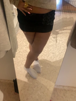 Svart kortkjol i bomull - Enkel och stilren svart kortkjol i mjukt bomullsmaterial. Kjolen har en rak passform och är perfekt att matcha med en stickad tröja eller crop top. Inga synliga detaljer eller mönster, vilket gör den lätt att styla till olika looks.