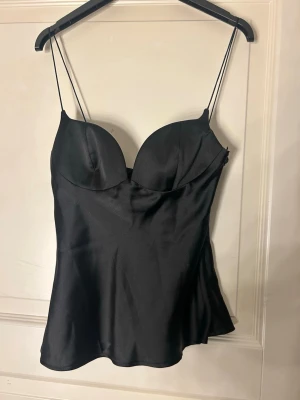 Söt topp från Zara❤️ - Säljer en super söt  svart stopp från Zara i storlek S. Toppen har tunna axelband, formade kupor och är i glansigt material🥰 