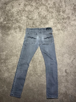 Grå Nudie Jeans - Säljer ett par grå jeans från Nudie Jeans! Perfekta för dig som gillar en clean och stilren look. Storleken är 31/32, hör av dig vid eventuella frågor!