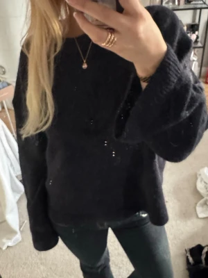 Mörkblå oversized stickad tröja - Mysig mörkblå stickad tröja med avslappnad, oversized passform och långa ärmar. Tröjan har en enkel design utan synliga mönster och är perfekt för lager på lager. Materialet ser ut att vara mjukt och bekvämt, troligen ull- eller akrylblandning.